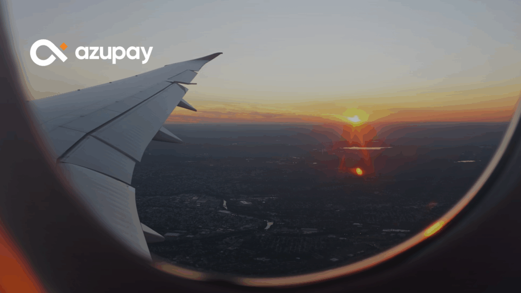 View from an airplane window at sunset showing the wing and landscape below, with Azupay’s logo on the top left corner.